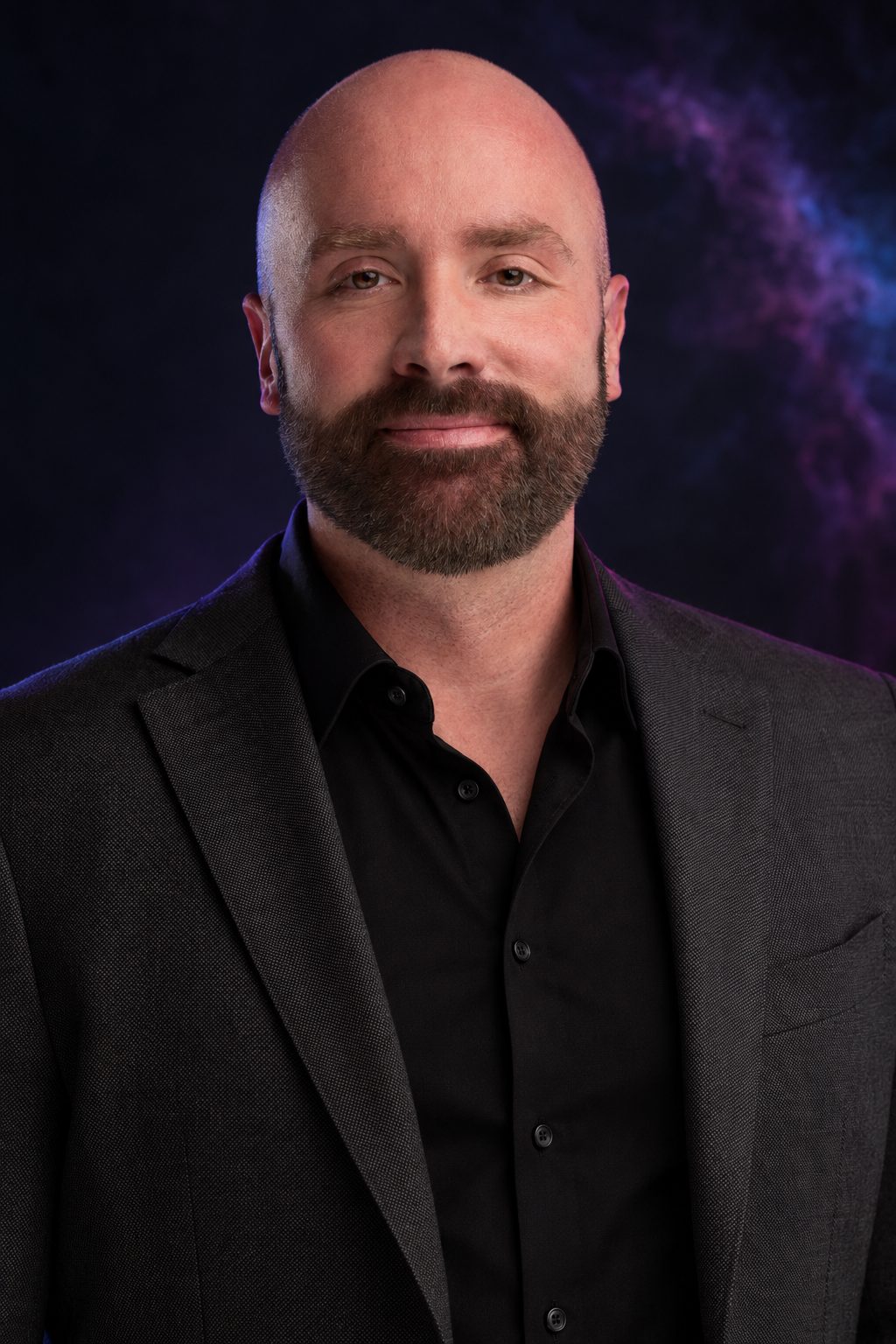 Portrait of Drew Bodine, Co-Founder of Nebulight Creative, in a charcoal suit and black shirt against a dark violet backdrop