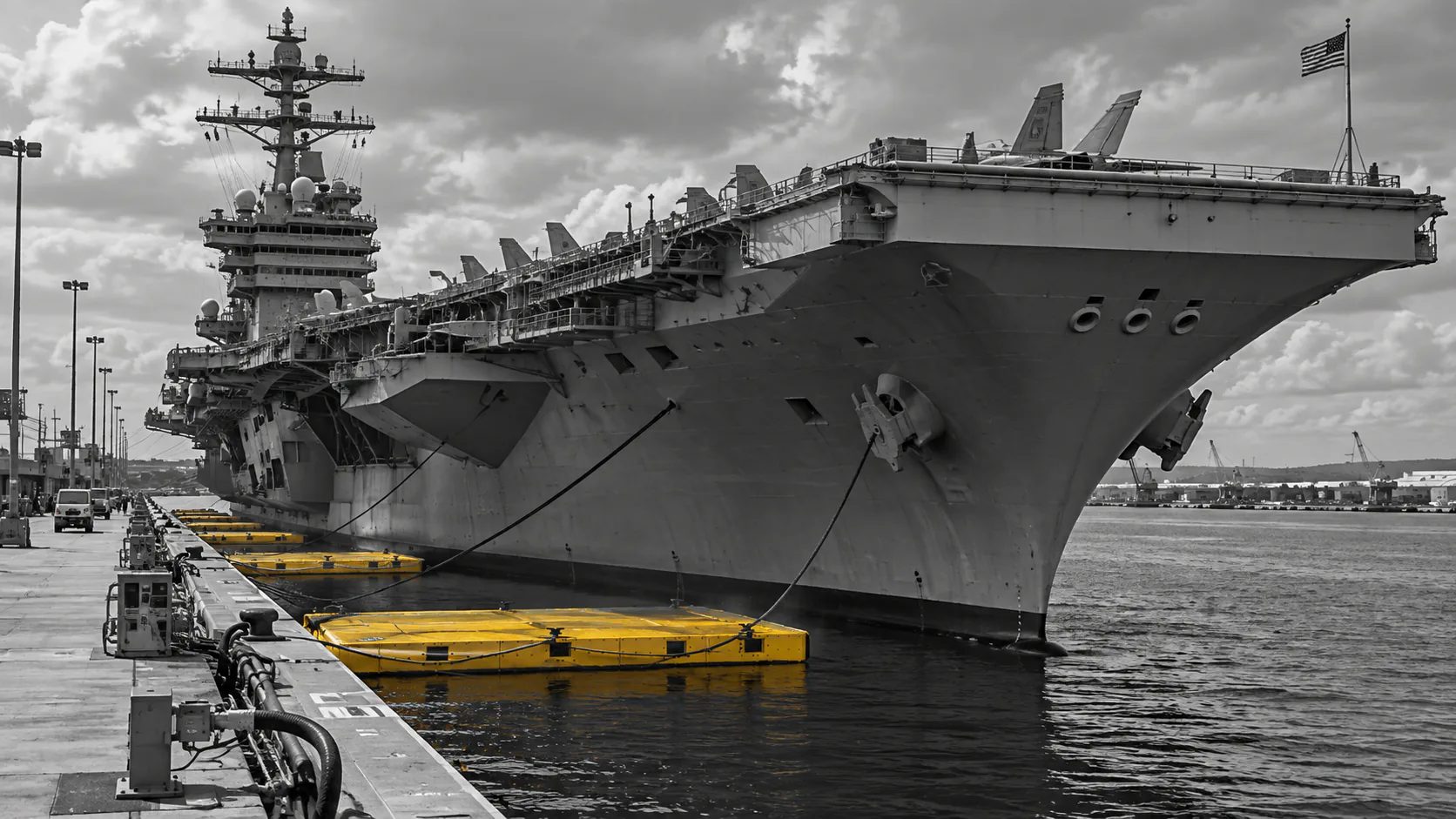 Visualization: an aircraft carrier moored pierside beside a row of yellow S.A.F.E. floating berthing platforms